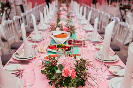 Long festive table served dishes and decorated with branches of greenery. Wedding banquet. Indoorの写真素材