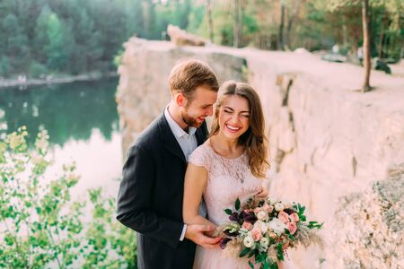 Attractive couple newlyweds bride and groom laugh and smile, happy and joyful moment. Wedding ceremony outdoors. Close-up portraitの写真素材
