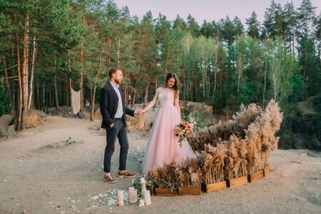 Newlyweds holding hands, laugh and smile, happy and joyful moment. Groom is looking on his beautiful bride. Outdoors wedding ceremonyの写真素材