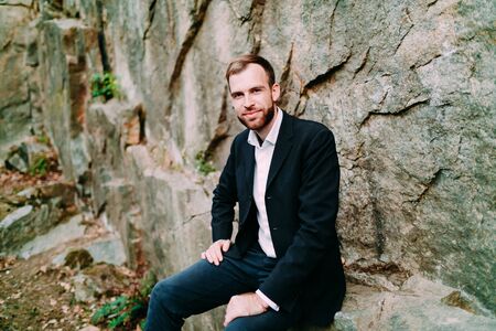 A stylish groom is smiling on the rock background, luxury boho wedding. Close-upの写真素材