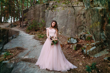 Bride with rustic wedding bouquet stands on the rock. Outdoorの写真素材