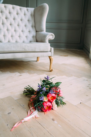 Rustic wedding bouquet with white roses, crimson peonies, and greens on a wooden floor. Indoors.の写真素材