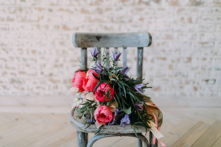Rustic wedding bouquet with white roses and crimson peonies on the aged gray wooden chair. close-up. Indoors.の写真素材