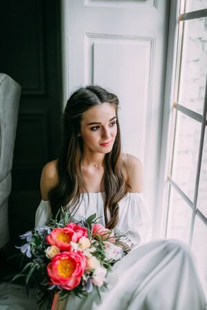 Woman by the window. Bride looking out the window, she waits for the groom.の写真素材