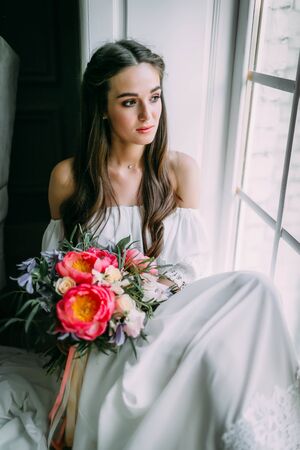 Woman by the window. Bride looking out the window, she waits for the groom.の写真素材