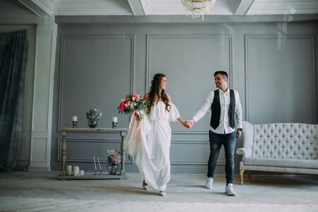 Cheerful bride hugging the groom. Newlyweds laughing and looking at each other . Artwork. Wedding indoors. Close-up. Selective, soft focusの写真素材