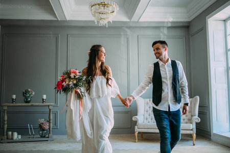 Cheerful bride hugging the groom. Newlyweds laughing and looking at each other . Artwork. Wedding indoors. Close-up. Selective, soft focusの写真素材