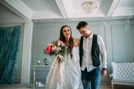 Cheerful bride and groom having fun together. Newlyweds laughing and go crazy. Artwork. Wedding indoors. Close-up. Selective, soft focusの写真素材