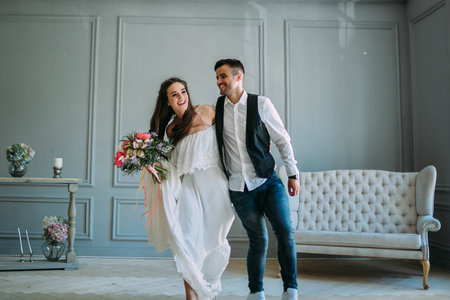 Cheerful bride and groom having fun together. Newlyweds laughing and go crazy. Artwork. Wedding indoors. Close-up. Selective, soft focusの写真素材