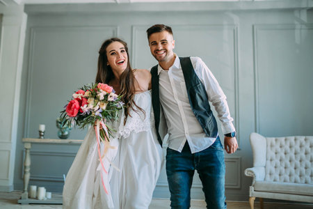 Cheerful bride and groom having fun together. Newlyweds laughing and go crazy. Artwork. Wedding indoors. Close-up. Selective, soft focusの写真素材