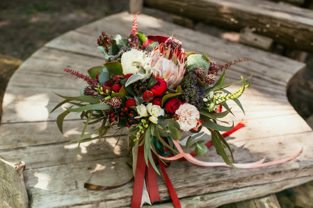 Rustic wedding bouquet with white and bordeaux roses, peonies, poppy and greens on an aged wooden floor. Close-up. Copy spaceの写真素材