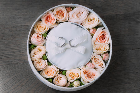 Wedding rings on white background in a pink round box with peach roses. Artwork. Soft focus. Top viewの写真素材