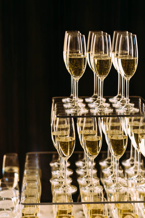 Champagne glasses standing in a tower at the party on a dark background. Artwork. Copy space for textの写真素材