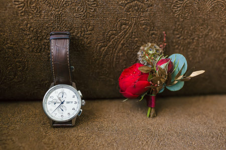 Stylish grooms accessories on a brown background. Boutonniere and wristwatches. Artwork