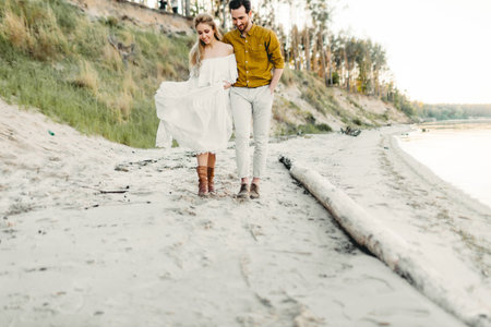 A young couple is having fun and walking on the sea coastline. Newlyweds looking at each other with tenderness. Romantic date on the beach. Wedding. Artworkの写真素材