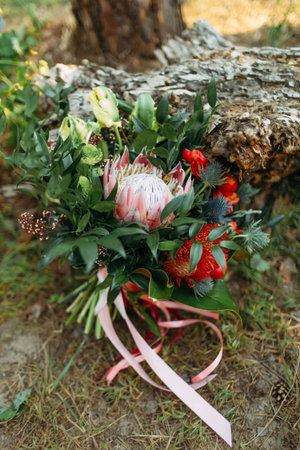 A rustic wedding bouquet with pink ribbons near the logの写真素材