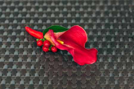 Wedding boutonniere from red calla on brown wicker texture. Close-up. Artwork