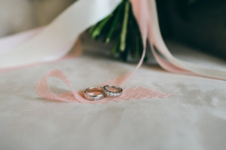 Silver wedding rings with gems on the piece of the ribbon. Close-up. Artworkの写真素材