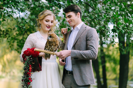 The owl sits on the girls hand. The bride and groom with the owl.の写真素材