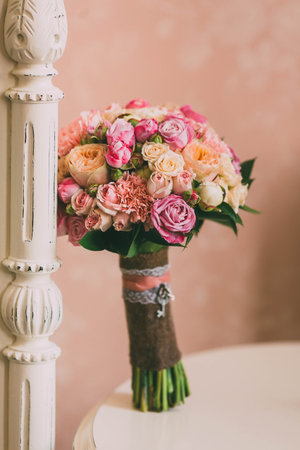 Bridal bouquet with pink roses and peach peonies stands on background of vintage wallの写真素材