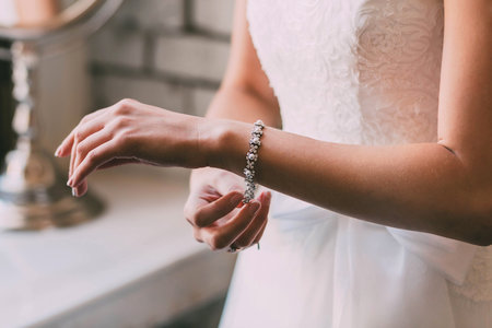 Bride fastens a bracelet. Wedding concept. Artwork. Soft focus on a handの写真素材