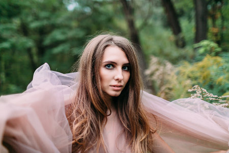 Portrait of beautiful caucasian girl with blue eyes in green leaves. Soft focusの写真素材