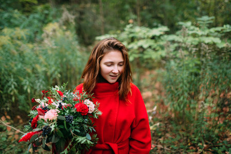 Beautiful young woman with rustic flowers. Happy girl smiling and holding bouquet outdoors. Autumn portrait of female in park.の写真素材