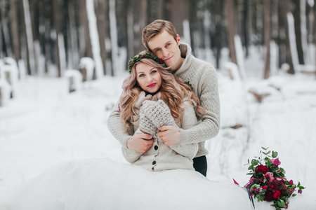 Newlyweds are hugging in the winter forest. Couple in love. Winter wedding ceremony.の写真素材