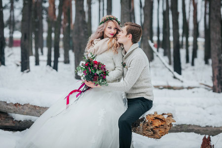Bride and groom with a bouquet are posing in snowy forest. Winter wedding. Artworkの写真素材