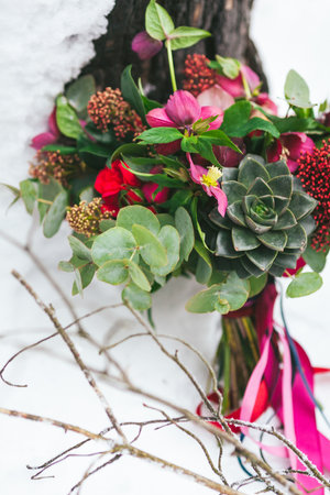 Rustic wedding bouquet with succulents and crimson flowers on the snow next to the tree. Outdoors. Artworkの写真素材