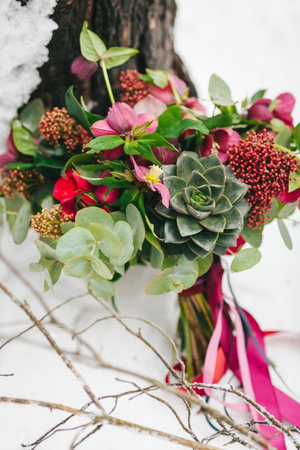 Rustic wedding bouquet with succulents and crimson flowers on the snow next to the tree. Outdoors. Artworkの写真素材
