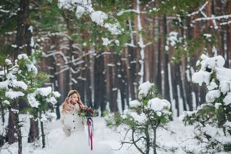 Young bride posing with bouquet in snowy forest. Winter wedding. Artwork. Copy spaceの写真素材