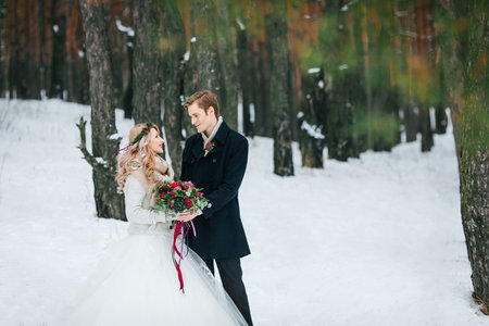 Couple in love are hugging on background of the snowy forest. Winter wedding.の写真素材
