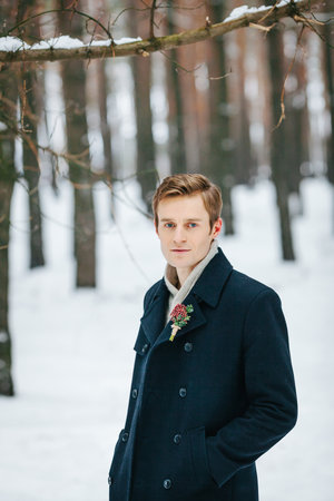 Handsome young groom in the winter forestの写真素材
