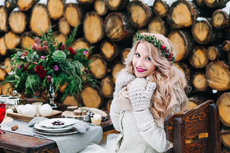 Cheerful bride in wreath and knitted mittens on background of decorated table. Winter weddingの写真素材