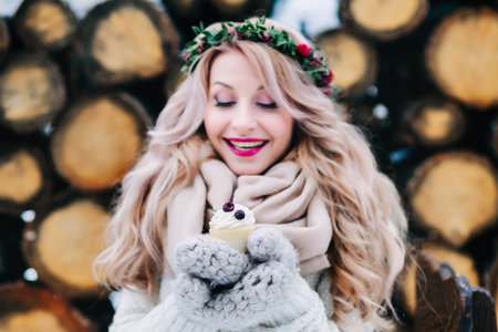Cheerful blonde girl with curly hair hold a cupcake. Selective focus on the cupcake. Artworkの写真素材