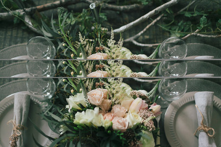 Rustic wedding decoration. A bouquet of different flowers on the decorated table for two.