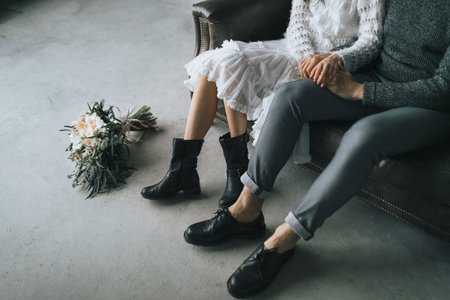 Newlyweds sit at home on the sofa. Legs in casual boots of young coupleの写真素材