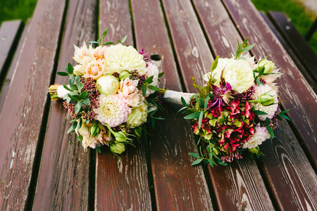 Two wedding bouquets of bride and bridesmaid lie on the brown wooden table. Artwork. Side viewの写真素材