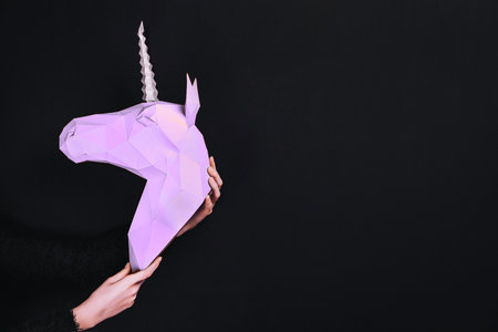 Hands hold a turquoise Unicorn. Artwork. 3d papercraft model of a unicorn. Copy spaceの写真素材
