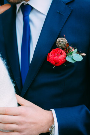 Wedding. Groom in a blue tuxedo with red rustic boutonniere. Boutonniere on the groom's jacket. Artworkの写真素材