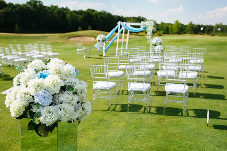 Hydrangea Flower Arrangements for Wedding. Blurred Rows of white chairs on green lawn before a wedding ceremonyの写真素材