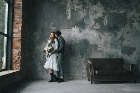 A Happy Couple is Hugging Next to the Panoramic Window. Groom is embrecing bride from the back. Artwork.の写真素材