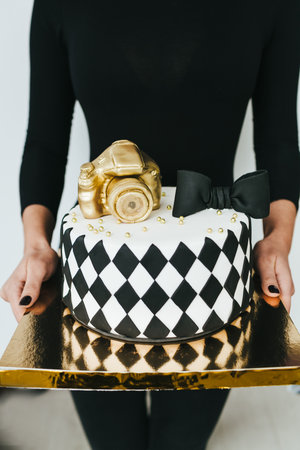 Young woman holding Black and White Birthday Cake For Photographer, closeupの写真素材