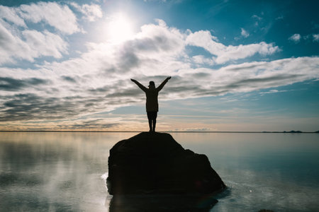 Rear view of a young happy woman enjoying journey, looking up and holding her hands in the air....
