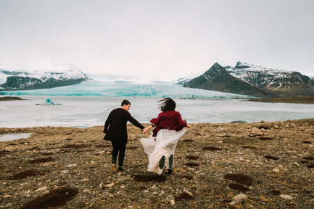 Bride and groom runs together. Iceland Wedding in Glacier Lagoon. Rear view. Artworkの写真素材