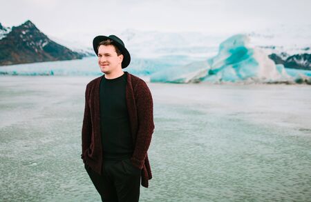 Portrait of handsome man in dark hat and casual clothes on glaciers background. Copy spaceの写真素材