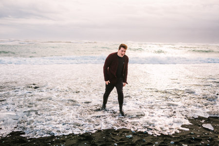 Traveler wet his feet in a cold water. Man in a cold water in Ice Lagoon. Iceland traveling. He is...