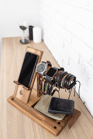Vertical Set of mans luxury multifunction accessories holder on table with white brick background. Handmade leather wallet and stylish watch. Multicolored Leather craft and a lot of hands bracelets.の写真素材