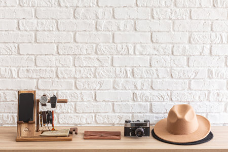 Men's casual accessories on wooden table over white brick wall background with place for text. Cellphone, wristwatch, retro photo camera and brown hat. elegant male accessories. の写真素材